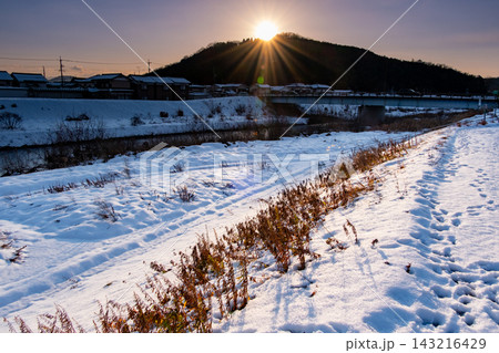 雪の日に袋川沿いから望む面影山に沈む夕日　鳥取県鳥取市大杙 143216429