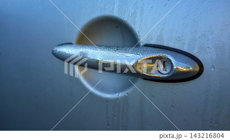 Blue car door handle with key cylinder, raindrops on wet paint, close-up of vehicle entry hardware outdoors in rain with macro detail for security and maintenance Blue car door handle with key cylinder, raindrops on wet paint, close-up of vehicle entry hardware outdoors in rain with macro detail for security and maintenance 143216804