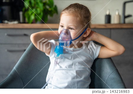 Cute little girl are sitting and holding a nebulizer mask leaning against the face, airway treatment concept 143216983