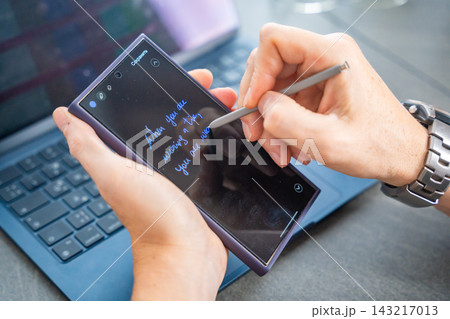 Close up view of man hand holding smart phone and stylus pen at his creative workspace. Close up view of man hand holding smart phone and stylus pen at his creative workspace. 143217013