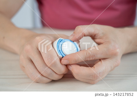 A woman is applying a continuous glucose monitoring sensor to her arm. A woman is applying a continuous glucose monitoring sensor to her arm. 143217852
