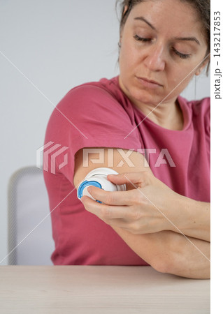 A woman is applying a continuous glucose monitoring sensor to her arm. 143217853