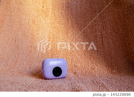 Purple container on orange textured background with soft lighting in a simple setting 143220690