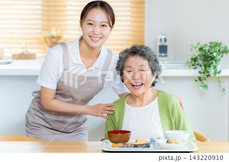 食事の準備をするヘルパーとシニア女性 143220910