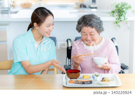 食事の介助をするヘルパーとシニア女性 食事の介助をするヘルパーとシニア女性 143220924