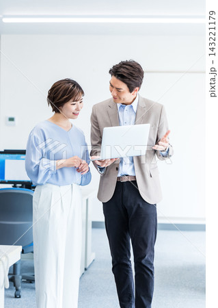 パソコンを見ながら打ち合わせする若い男女 パソコンを見ながら打ち合わせする若い男女 143221179