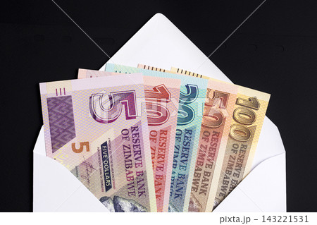 Zimbabwean dollar in a white envelope on a black background Zimbabwean dollar in a white envelope on a black background 143221531