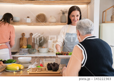 Caucasian family with adult daughter preparing food together in kitchen Caucasian family with adult daughter preparing food together in kitchen 143222363