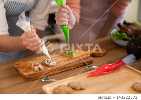 Close up of women hands decorating gingerbread cookies with icing Close up of women hands decorating gingerbread cookies with icing 143222372