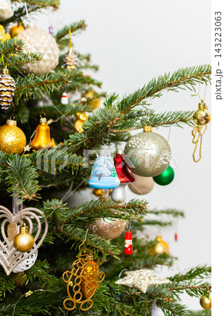 A Christmas tree stands in a warm room filled with decorations. Colorful ornaments hang from the branches while lights add a festive touch. People gather around to enjoy the holiday spirit A Christmas tree stands in a warm room filled with decorations. Colorful ornaments hang from the branches while lights add a festive touch. People gather around to enjoy the holiday spirit 143223063