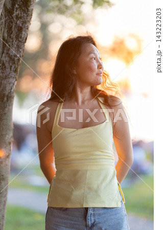 Asian woman enjoying golden hour sunset in park Asian woman enjoying golden hour sunset in park 143223203