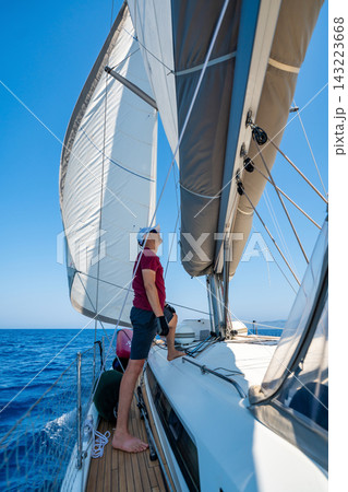 Man monitoring the mainsail while sailing a yacht offshore. Seamanship and navigation skills during a long distance voyage. 143223668