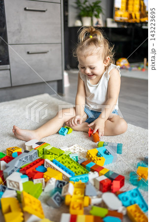 Caucasian child a little girl is playing in the constructor at home. Educational toys for children. Caucasian child a little girl is playing in the constructor at home. Educational toys for children. 143223695