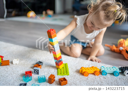 Caucasian child a little girl is playing in the constructor at home. Educational toys for children. 143223715
