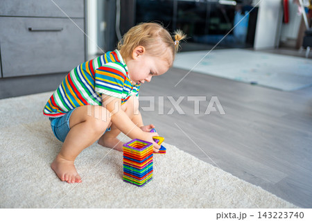 Little girl playing colorful magnet plastic blocks kit at home. The child playing educational games. Early childhood development. Little girl playing colorful magnet plastic blocks kit at home. The child playing educational games. Early childhood development. 143223740