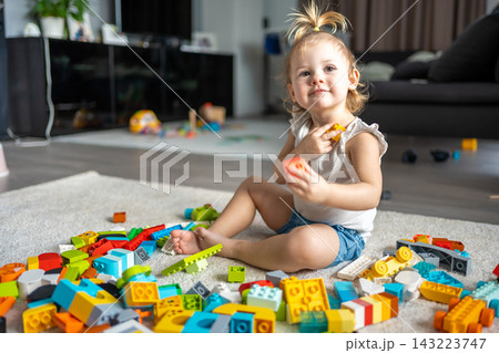Caucasian child a little girl is playing in the constructor at home. Educational toys for children. 143223747