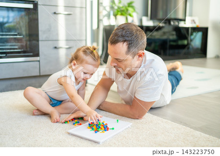 Cute little girl playing with mushroom nail mosaic. Father and baby playing together concept. Hobby and leisure time. Cute little girl playing with mushroom nail mosaic. Father and baby playing together concept. Hobby and leisure time. 143223750