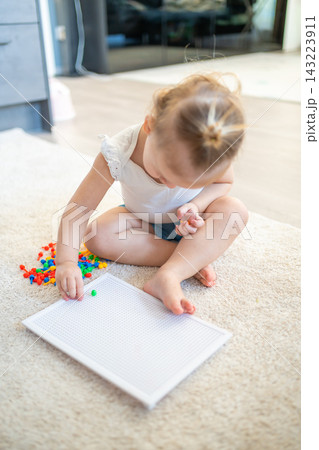 Pretty little girl playing with mushroom nail mosaic at home. Hobby and leisure time Pretty little girl playing with mushroom nail mosaic at home. Hobby and leisure time 143223911