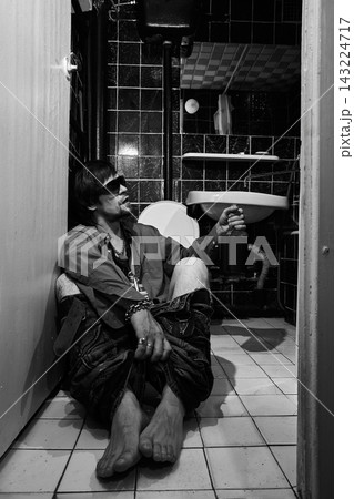 Drunk Man Sitting on Bathroom Floor with Alcohol Bottle Drunk Man Sitting on Bathroom Floor with Alcohol Bottle 143224717