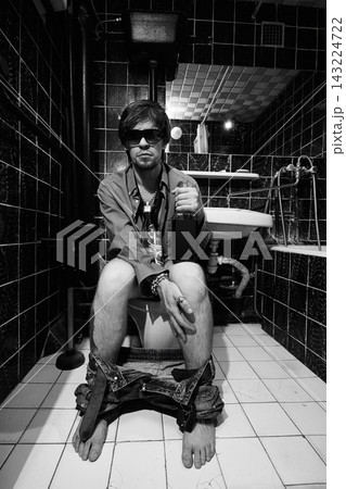 Serious Intoxicated Man Sitting on Toilet with Bottle Serious Intoxicated Man Sitting on Toilet with Bottle 143224722