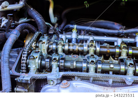 Mechanics are inspecting engine parts in vehicle engine bay at garage during maintenance work Mechanics are inspecting engine parts in vehicle engine bay at garage during maintenance work 143225531