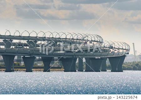 cars move along the expressway on poles in the water in clear sunny weather, lampposts above the road cars move along the expressway on poles in the water in clear sunny weather, lampposts above the road 143225674