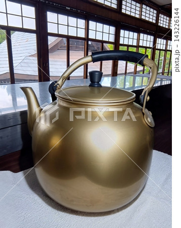 木枠窓の室内とお盆に置かれた大きな昭和レトロ風の金色アルミやかん 木枠窓の室内とお盆に置かれた大きな昭和レトロ風の金色アルミやかん 143226144