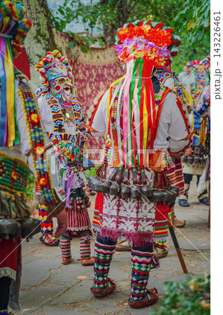Kukeri Performer back view. Kukeri performers in colorful traditional Bulgarian folk costumes with ribbons, decorative mask, large cowbells. Balkan ritual clothing, cultural festival in Kotel Kukeri Performer back view. Kukeri performers in colorful traditional Bulgarian folk costumes with ribbons, decorative mask, large cowbells. Balkan ritual clothing, cultural festival in Kotel 143226461