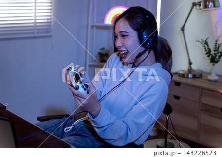 Young Asian Woman Gaming at Home with Controller During Live Streaming Session 143226523