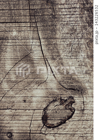 Weathered wooden surface displaying deep cracks and a prominent knot, creating a natural texture and rustic background pattern ideal for design projects. Weathered wooden surface displaying deep cracks and a prominent knot, creating a natural texture and rustic background pattern ideal for design projects. 143226532