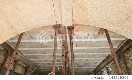 Adjustable steel props support a ceiling during structural home renovation. Concepts: construction safety, temporary support, building repair, structural reinforcement. 143226561