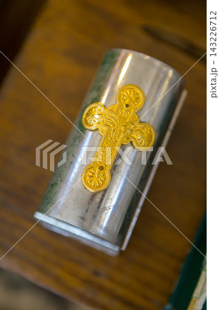 Small silver container with a gold cross design placed on a wooden surface Small silver container with a gold cross design placed on a wooden surface 143226712