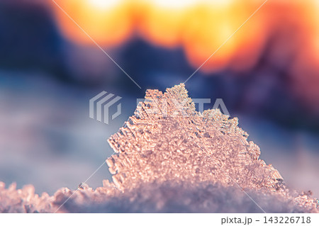Snowflake resting on a soft layer of snow at sunset Snowflake resting on a soft layer of snow at sunset 143226718