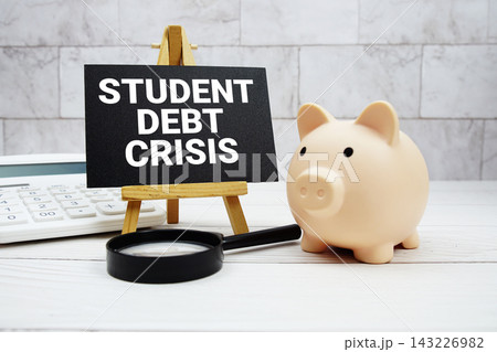 Student Debt Crisis text  with piggy bank, calculator and magnifying glass 143226982
