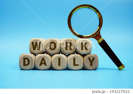 Work Daily alphabet letters wooden cube and magnifying glass on blue background 143227022