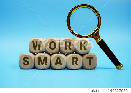 Work Smart alphabet letters wooden cube and magnifying glass on blue background 143227023