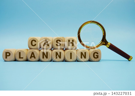 Cash Planning alphabet letters wooden cube and magnifying glass on blue background Cash Planning alphabet letters wooden cube and magnifying glass on blue background 143227031