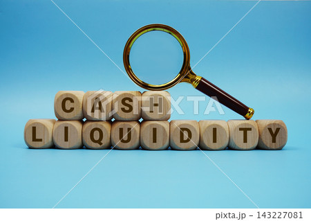 Cash Liquidity alphabet letters wooden cube and magnifying glass on blue background Cash Liquidity alphabet letters wooden cube and magnifying glass on blue background 143227081