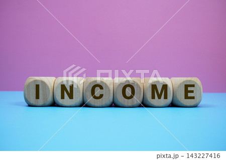 INCOME alphabet letters wooden cube with alarm clock on pink and blue background INCOME alphabet letters wooden cube with alarm clock on pink and blue background 143227416