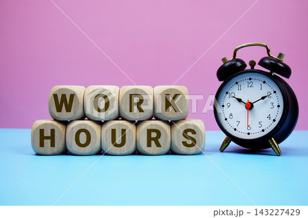 Work Hours alphabet letters wooden cube with alarm clock on pink and blue background Work Hours alphabet letters wooden cube with alarm clock on pink and blue background 143227429