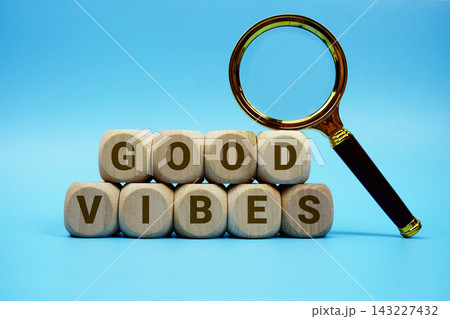 Good Vibes alphabet letters wooden cube and magnifying glass on blue background 143227432