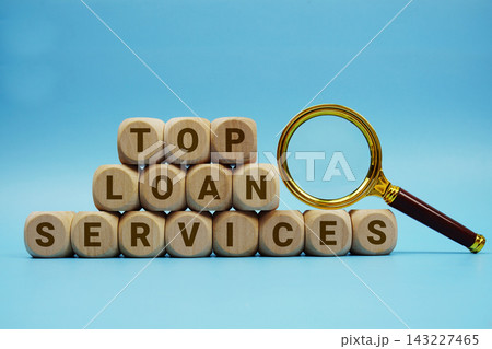 Top Loan Services alphabet letters wooden cube and magnifying glass on blue background Top Loan Services alphabet letters wooden cube and magnifying glass on blue background 143227465