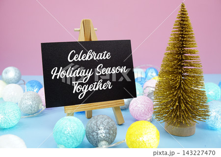 Celebrate Holiday Season Together text with mini Christmas tree and LED cotton balls decoration on pink and blue background Celebrate Holiday Season Together text with mini Christmas tree and LED cotton balls decoration on pink and blue background 143227470