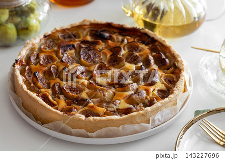 Golden brown fig tart freshly baked with flaky crust served on white plate with golden fork 143227696