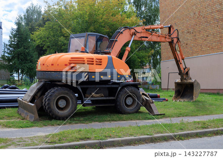 Heavy orange wheeled excavator at a work site on a city street 143227787