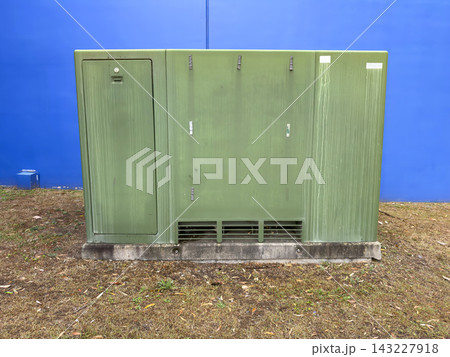 An old and weathered electrical transformer near a commercial building 143227918