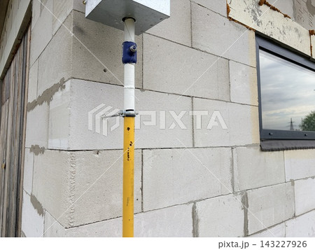 A yellow gas pipe mounted on an unfinished aerated concrete block wall A yellow gas pipe mounted on an unfinished aerated concrete block wall 143227926