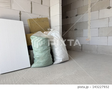 an unfinished room featuring grey aerated concrete block walls and a smooth concrete floor. Home renovation, thermal insulation, and building construction. an unfinished room featuring grey aerated concrete block walls and a smooth concrete floor. Home renovation, thermal insulation, and building construction. 143227932