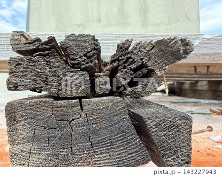 Close-up of a badly burnt and charred wooden post with a split top. Fire damage, destruction, and decay. Close-up of a badly burnt and charred wooden post with a split top. Fire damage, destruction, and decay. 143227943