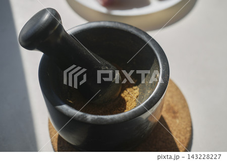 Ground spices in black mortar with pestle beside raw meat Ground spices in black mortar with pestle beside raw meat 143228227